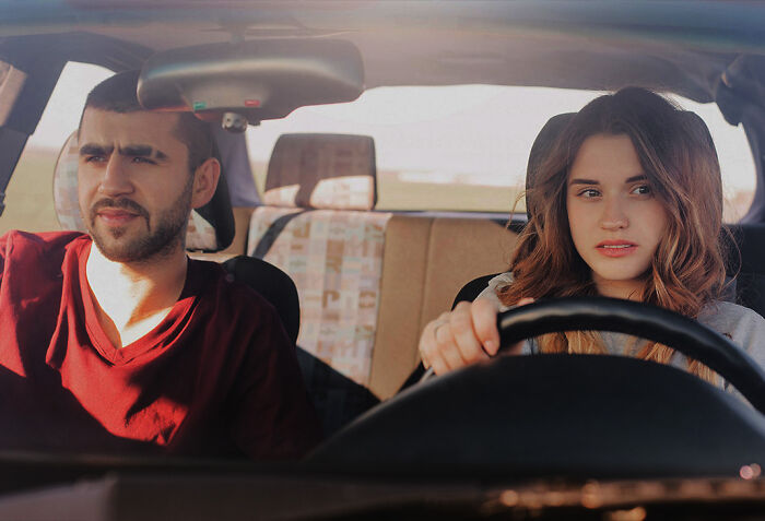 A man and a woman in a car, the woman driving with a worried expression, highlighting potential first date red flags.