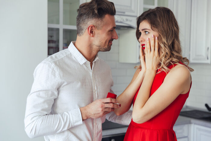 A man proposing to a surprised woman in a kitchen. Sometimes a first date has shocking red flags.