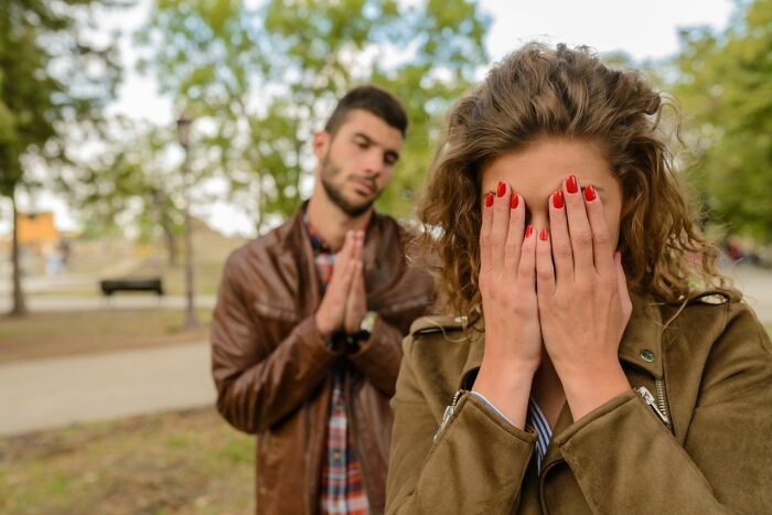 A woman crying, covering her face as a man tries to apologize behind her; a scene depicting first date red flags.
