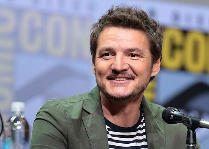 Close-up of a smiling celebrity Pedro Pascal with a beard, wearing a striped shirt and green jacket. It's one of the worst moments people asked celebrities for a photo.