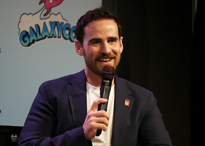 A man with a microphone, smiling, at a GalaxyCon event, representing a moment someone asked a celebrity for a photo.