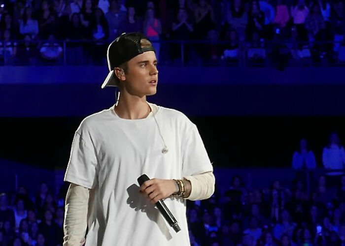 Justin Bieber on stage holding a microphone. One of the worst moments people asked celebrities for a photo.
