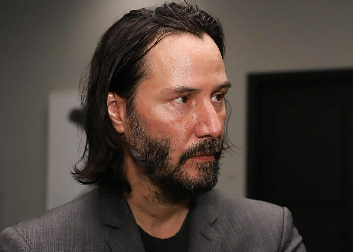Keanu Reeves in a close-up, looking thoughtful, representing a moment someone asked a celebrity for a photo.