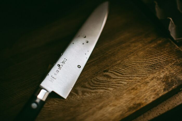 A close-up of a sharp kitchen knife with water droplets, hinting at a tense babysitting story.