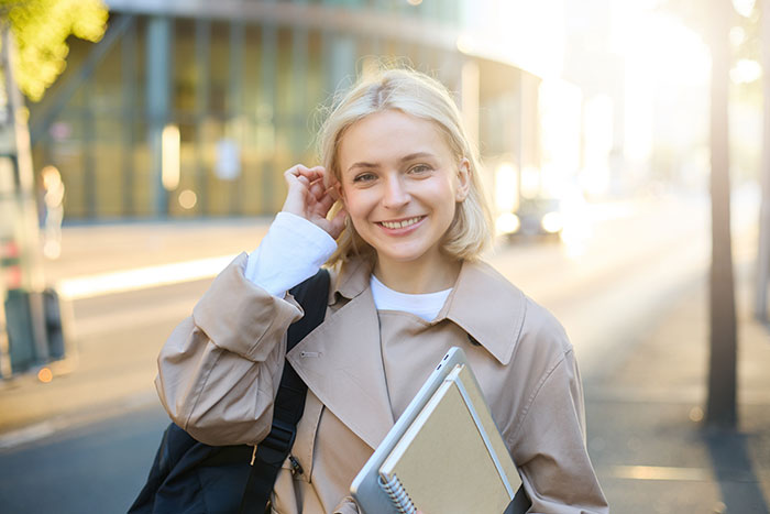 A smiling teen escapes controlling mom, walking outdoors with a backpack and notebooks after body lies. A smiling teen escapes controlling mom, walking outdoors with a backpack and notebooks after body lies.