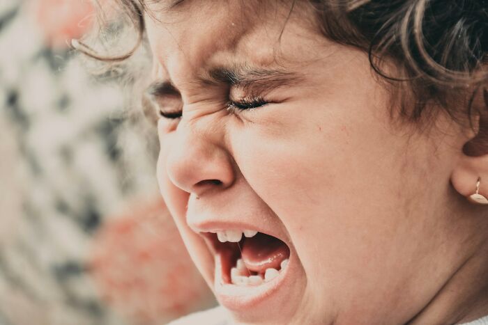 A young child crying intensely, expressing distress, possibly from a scary public encounter.