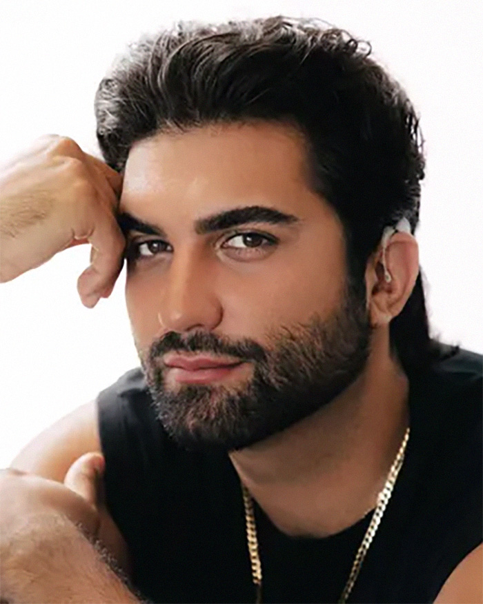 A close-up of a man with dark hair and a beard, wearing a black shirt and a gold chain, for Zendaya's latest look. A close-up of a man with dark hair and a beard, wearing a black shirt and a gold chain, for Zendaya's latest look.