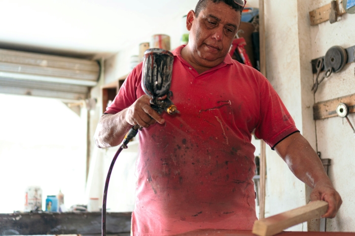A blue-collar husband working with a spray gun and wood, covered in paint, highlighting a new trend about women. A blue-collar husband working with a spray gun and wood, covered in paint, highlighting a new trend about women.