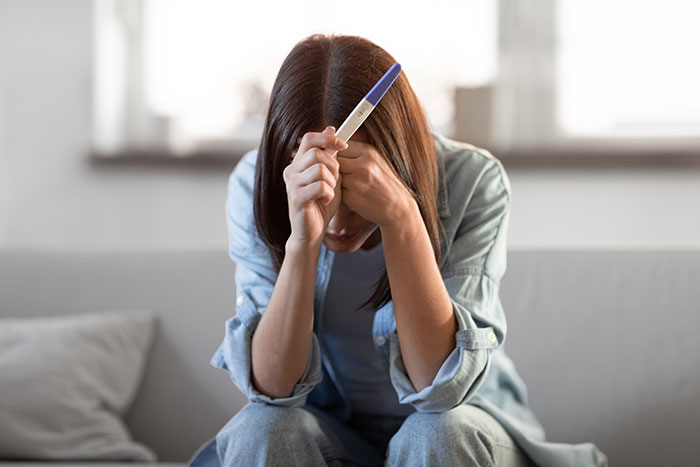 A woman is seen looking worried while holding a positive pregnancy test, highlighting how friends spouses are sleeping together. A woman is seen looking worried while holding a positive pregnancy test, highlighting how friends spouses are sleeping together.