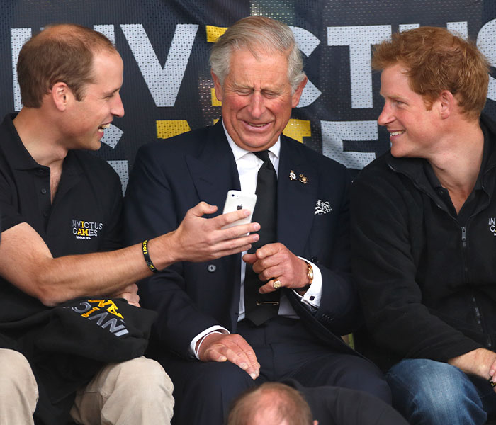 Prince William shows King Charles a phone, with Prince Harry laughing alongside, reflecting tension. Prince William shows King Charles a phone, with Prince Harry laughing alongside, reflecting tension.