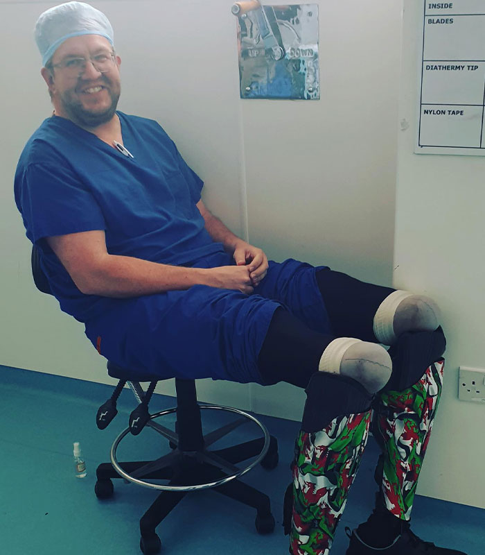 Smiling surgeon in scrubs with his legs frozen for amputation, highlighting the horrific crimes.