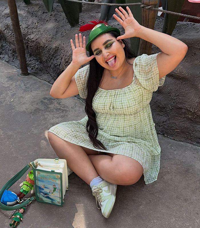 The Peter Pan girl makes a funny face while sitting on the ground, showcasing her Peter Pan obsession.