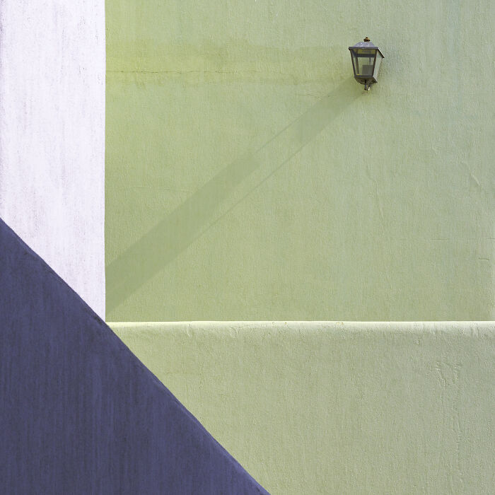 An abstract minimalist photography composition featuring a golden wall, light green wall, and turquoise sky, creating sharp angles.