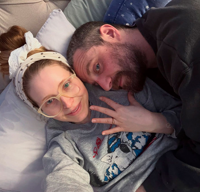 Harry Potter star Jessie Cave, an adult creator, lies in bed with a partner, smiling at the camera. Harry Potter star Jessie Cave, an adult creator, lies in bed with a partner, smiling at the camera.