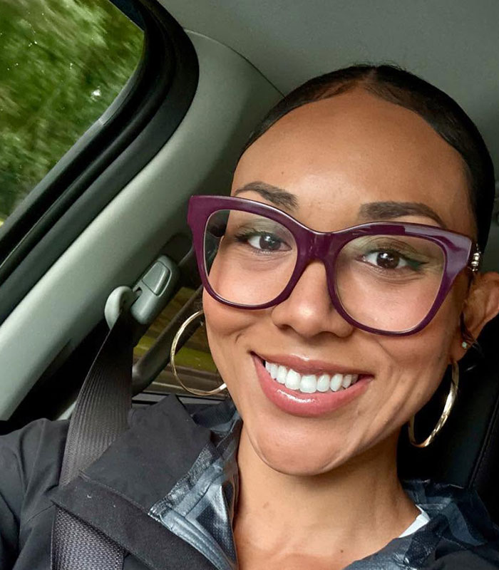 A smiling surrogate in purple glasses and a seatbelt, reflecting on her fight to end pregnancy. A smiling surrogate in purple glasses and a seatbelt, reflecting on her fight to end pregnancy.