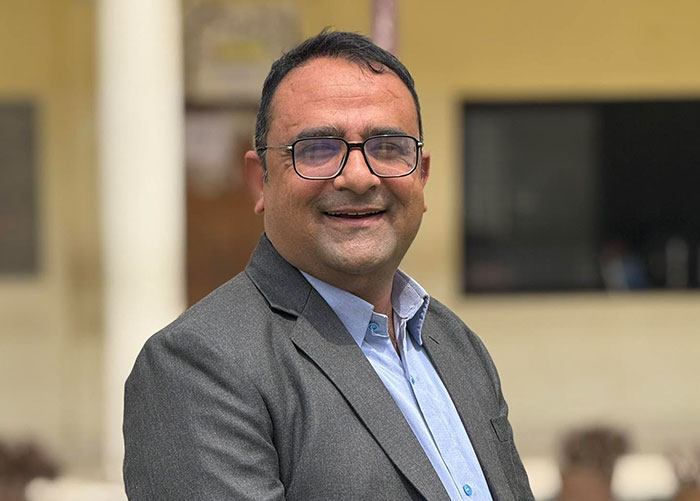 The hero teacher, wearing a grey suit jacket, smiling after saving children from Nepal floods. The hero teacher, wearing a grey suit jacket, smiling after saving children from Nepal floods.
