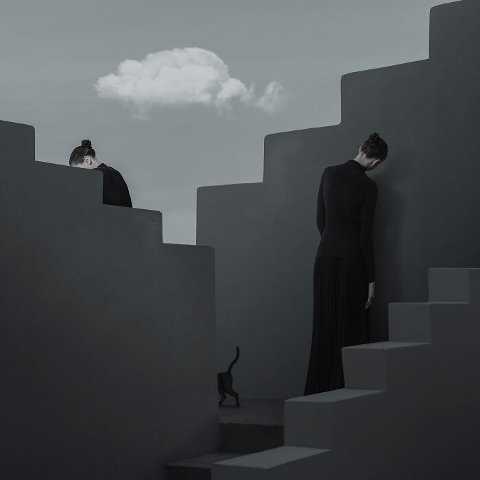 Minimalist photography showing two women and a black cat navigating a striking, monochromatic set of stairs under a single cloud.