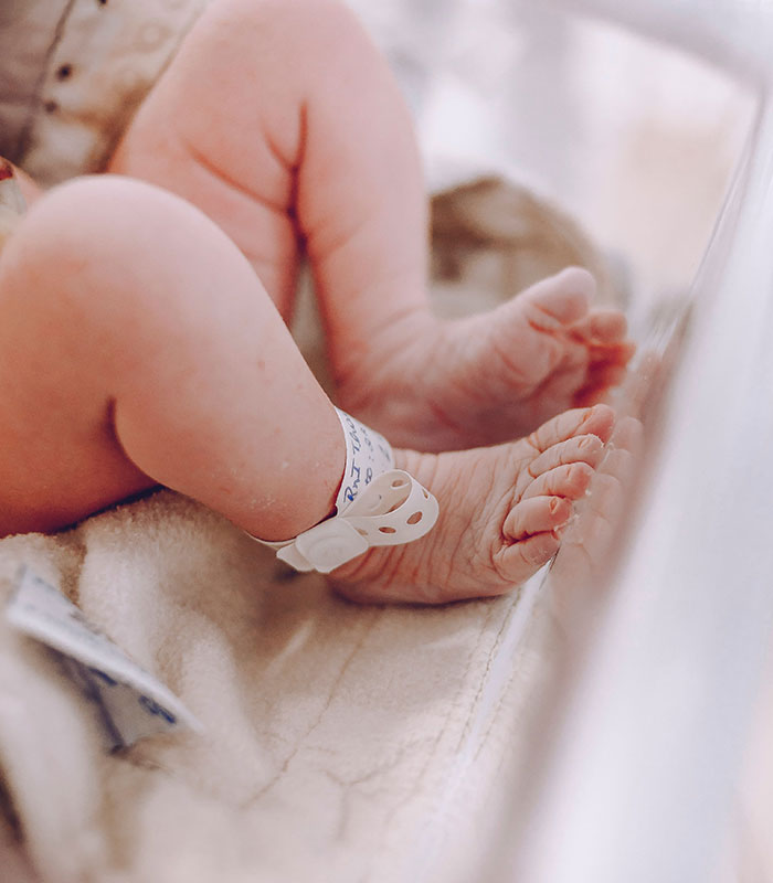 Close-up of a newborn baby's feet with hospital bands, born from the surrogate who fought parents wishes. Close-up of a newborn baby's feet with hospital bands, born from the surrogate who fought parents wishes.