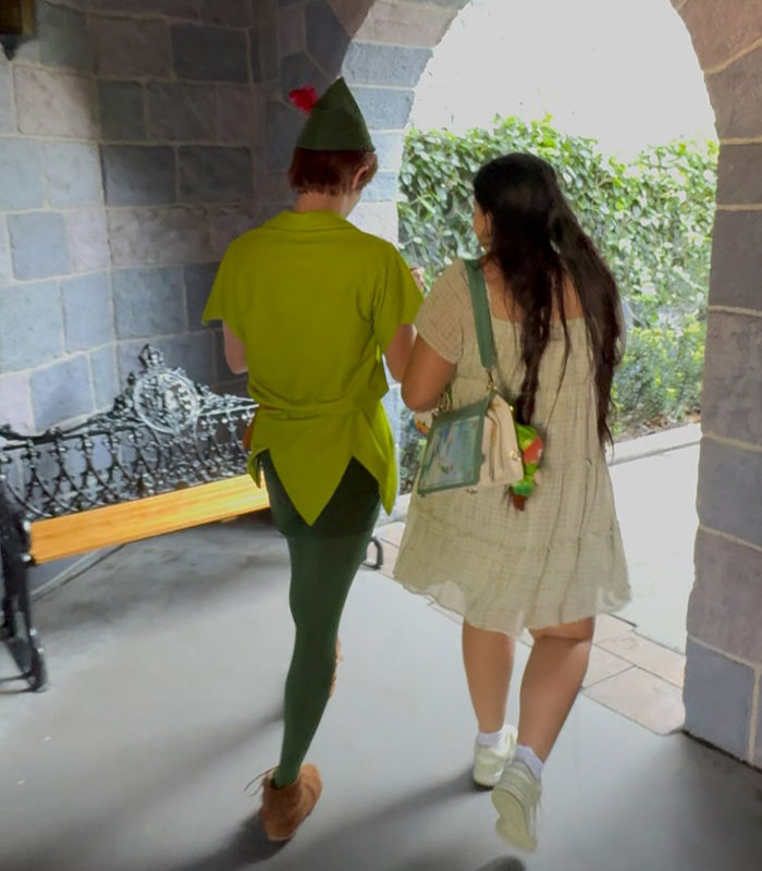 The Peter Pan girl walks beside a Peter Pan character, highlighting her viral Peter Pan obsession.