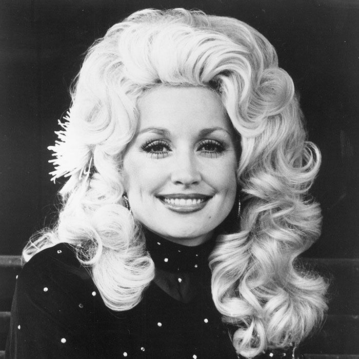 A beautiful black and white portrait of a young Dolly Parton with her signature big blonde hair. A beautiful black and white portrait of a young Dolly Parton with her signature big blonde hair.