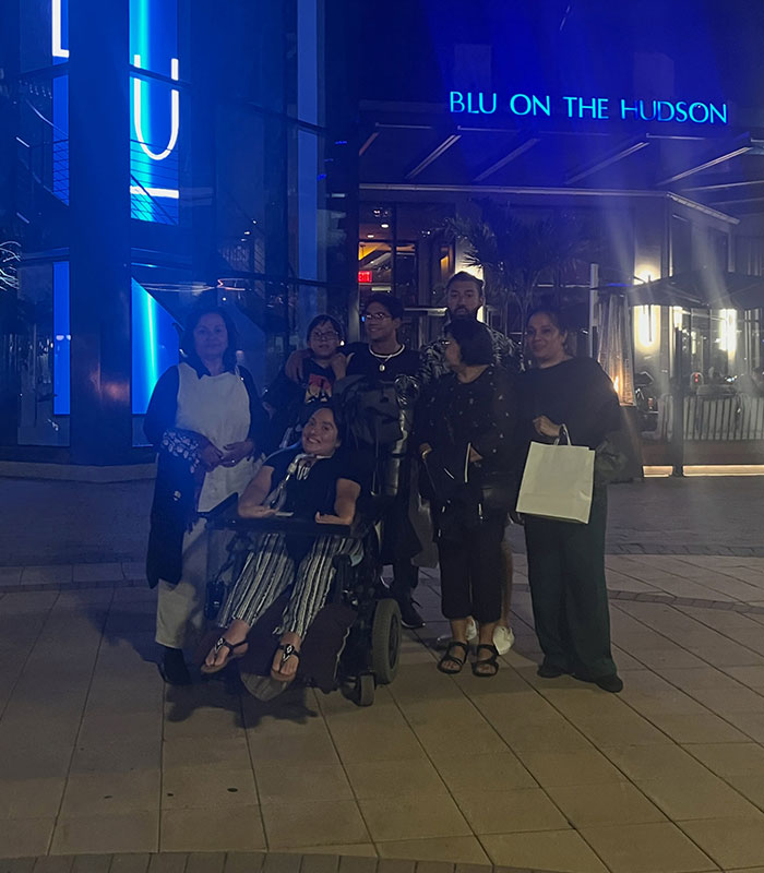 Disabled customer in a wheelchair with family outside a restaurant at night. Restaurant breaks silence after offensive birthday message.