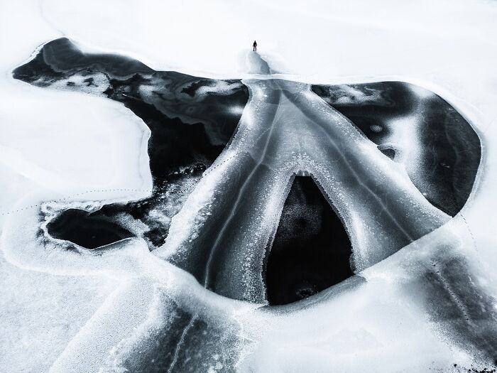 A human-like figure surrounded by intricate, flowing patterns on a dark surface, a compelling piece of minimalist photography.