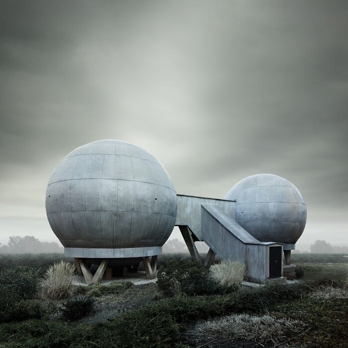 A minimalist photography awards image of two large spherical buildings connected by a walkway, set against a cloudy sky.