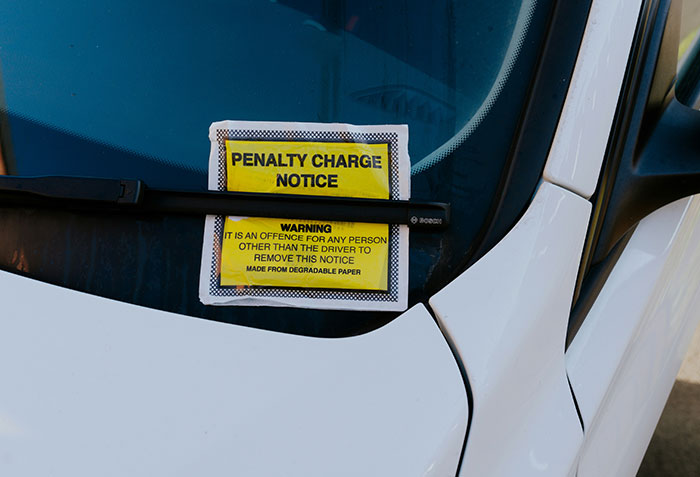 A close-up of a penalty charge notice on a car windshield, part of an unusual strategy for tourists. A close-up of a penalty charge notice on a car windshield, part of an unusual strategy for tourists.