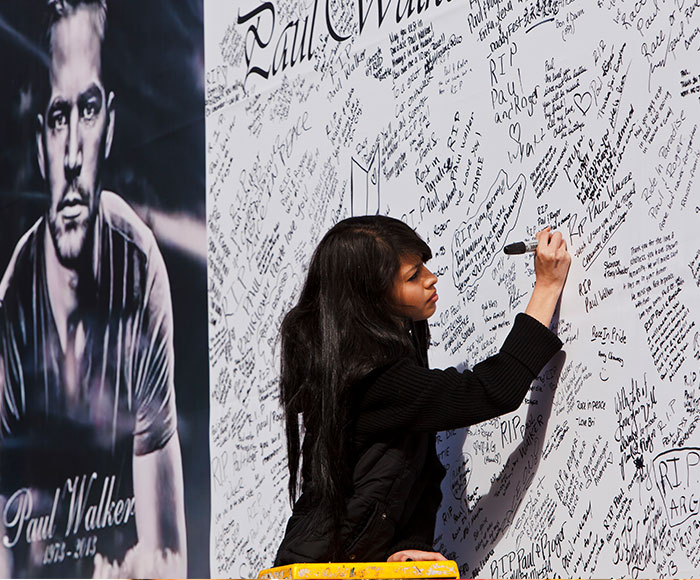 Paul Walker controversy memorial: A fan signing a tribute wall for Paul Walker, amidst resurfaced age gap discussions.