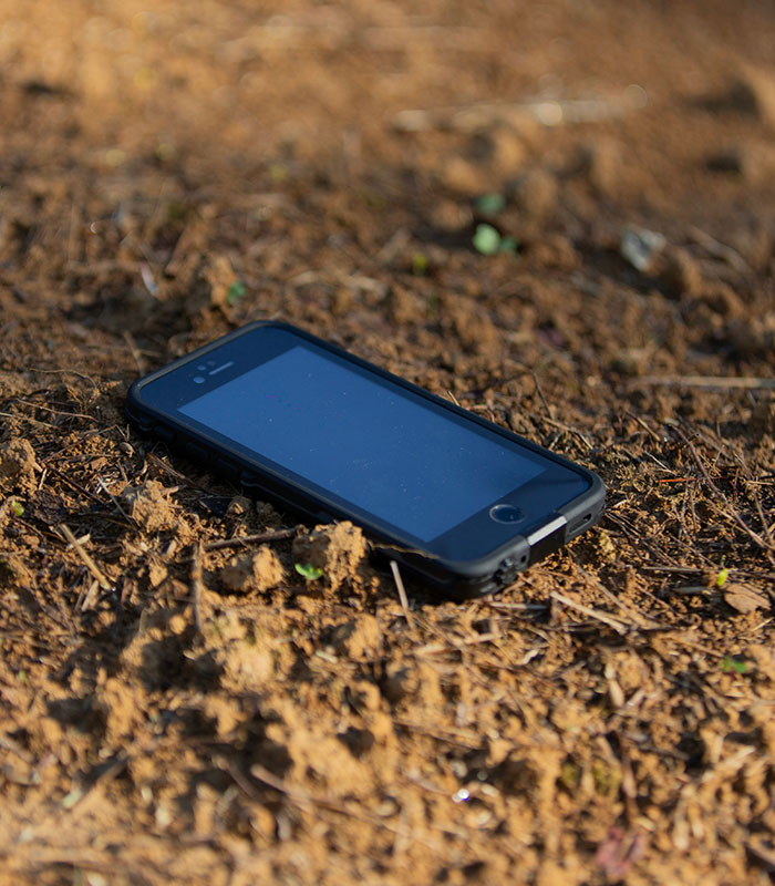 A smartphone lying on the dirt ground, representing the phone call that occurred after the car crash.