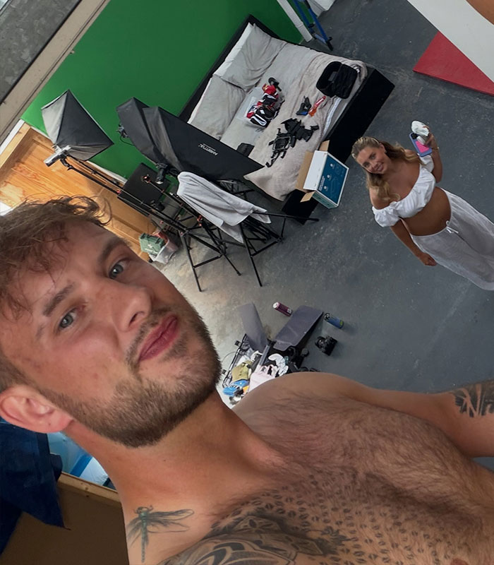 Man posing for a selfie in front of Bonnie Blue at a raunchy baby shower.