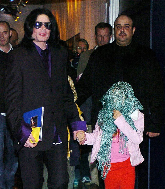 Michael Jackson holding hands with a young child, revealing details about life and accusations. Michael Jackson holding hands with a young child, revealing details about life and accusations.