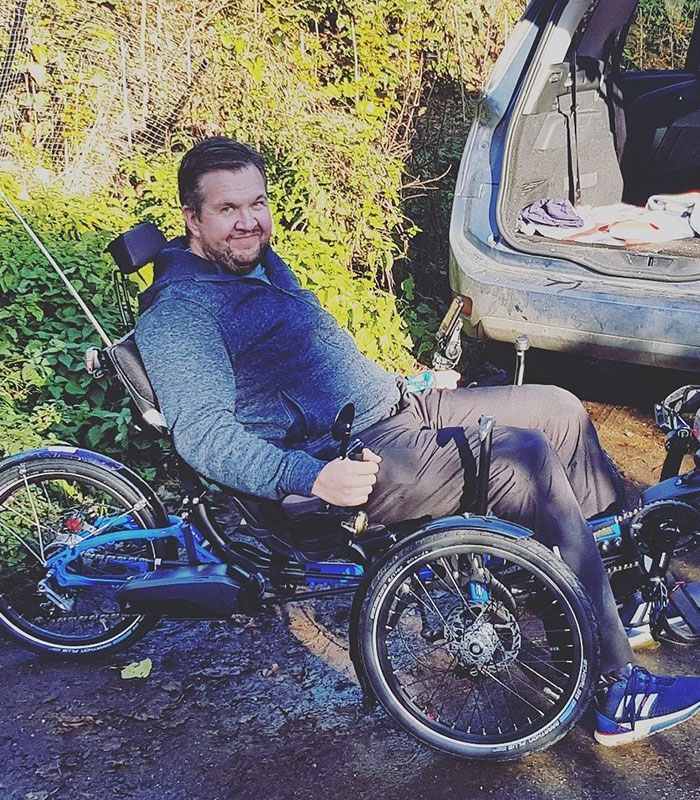 A man with amputated legs in a specialized recumbent bicycle, recovering from the surgeon's horrific crimes.