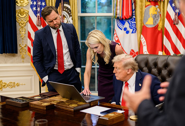 A glamorous aide points at a laptop screen with Trump and another man in a security leak image. A glamorous aide points at a laptop screen with Trump and another man in a security leak image.