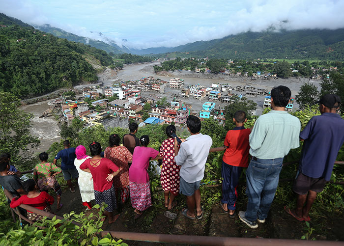 A group of people standing on a hill, overlooking a town affected by Nepal floods, showing the impact. A group of people standing on a hill, overlooking a town affected by Nepal floods, showing the impact.