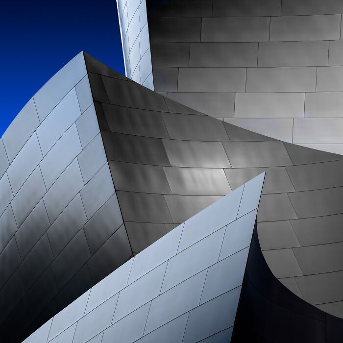 Detail of modern architecture with curved and angular metallic panels against a deep blue sky, an extraordinary minimalist photography.
