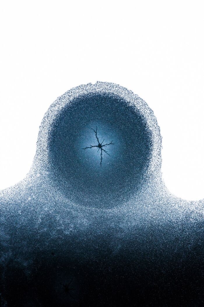 Extraordinary minimalist photography of a dark blue ice circle with a central crack on a white background, from the Minimalist Photography Awards.