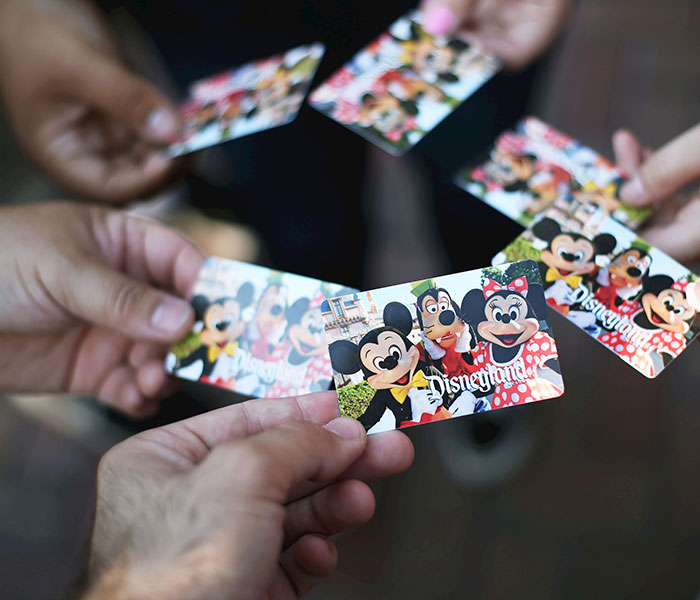 Hands holding various Disney cruise cards featuring Mickey Mouse, Goofy, and Minnie Mouse characters.