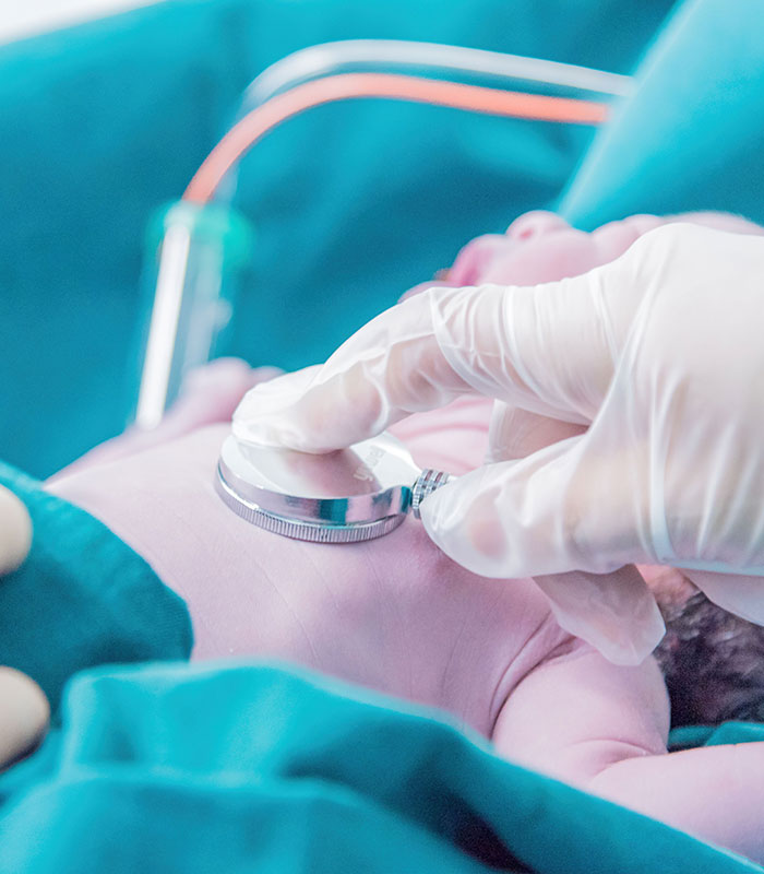 Medical professional uses a stethoscope on a newborn baby after a surrogate birth. Medical professional uses a stethoscope on a newborn baby after a surrogate birth.