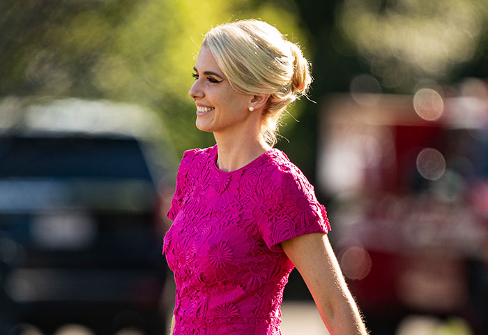 A glamorous aide in a bright pink dress smiles, highlighting the security leak context. A glamorous aide in a bright pink dress smiles, highlighting the security leak context.