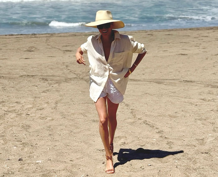 Meghan Markle walking on a sandy beach, wearing an oversized shirt, shorts, and a wide-brimmed hat, perhaps after an acting comeback was scrapped.