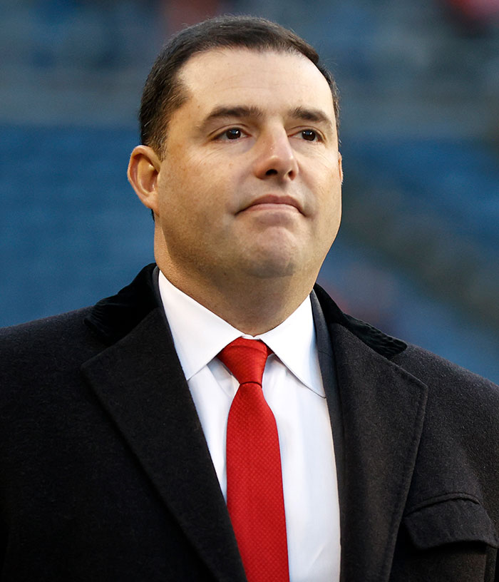 49ers Owner Jed York in a black coat and red tie, looking serious, after his trailer park arrest.
