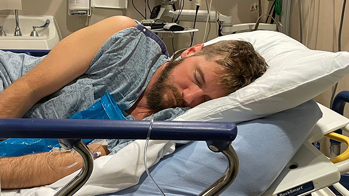A man lies in a hospital bed with an IV drip, injured from the incident where the bride's life was taken. A man lies in a hospital bed with an IV drip, injured from the incident where the bride's life was taken.
