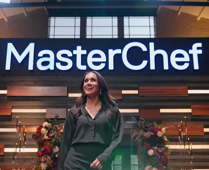 Meghan Markle smiling under a MasterChef sign, potentially related to her acting comeback.