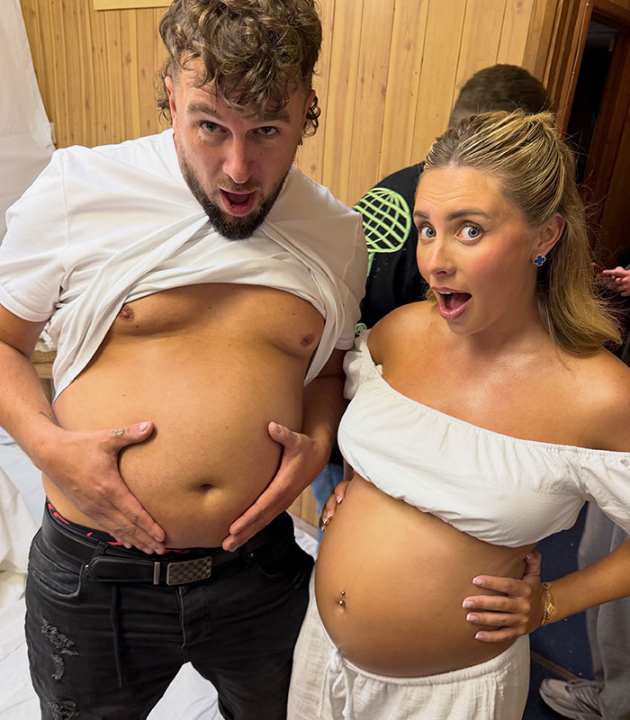 A man with his shirt pulled up to expose his belly next to a pregnant Bonnie Blue at a raunchy baby shower.