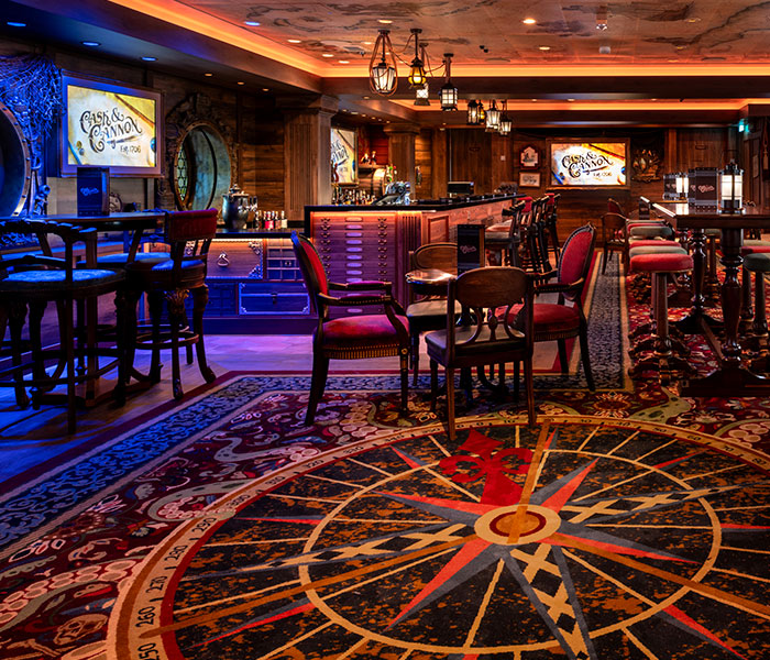 The interior of a Disney cruise bar and lounge with maritime decor and a compass rose on the floor.