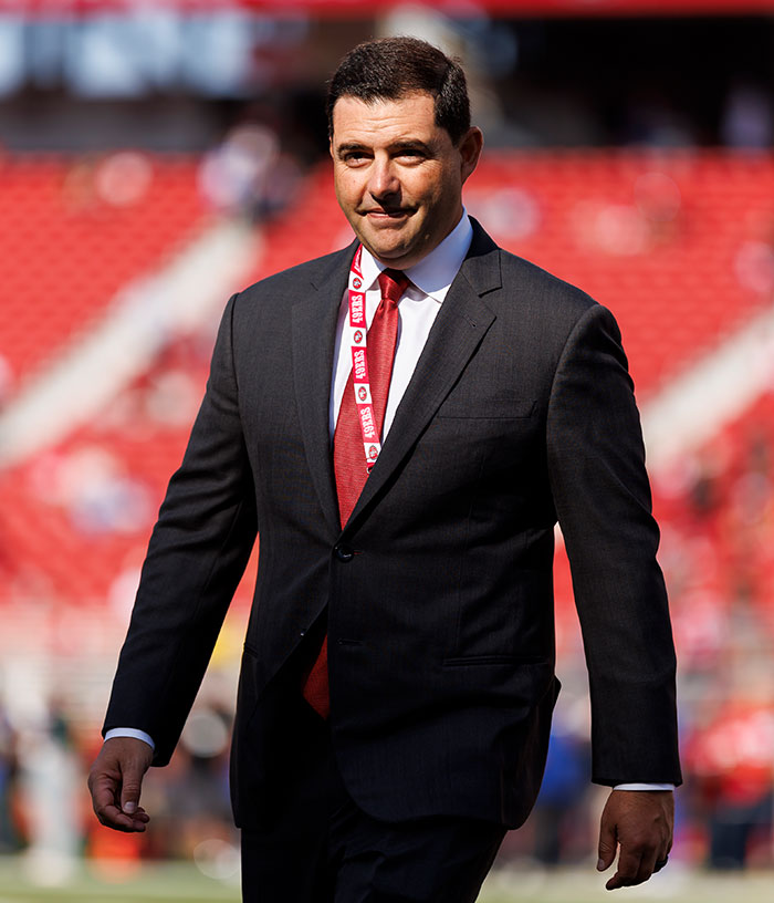 49ers Owner Jed York walking on a field in a suit and red tie, before or after his trailer park arrest. 49ers Owner Jed York walking on a field in a suit and red tie, before or after his trailer park arrest.
