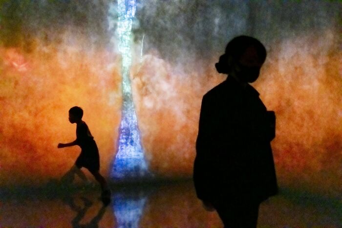 Best street photos from the Macadam Awards feature silhouettes of a child and an adult against a colorful, abstract light.