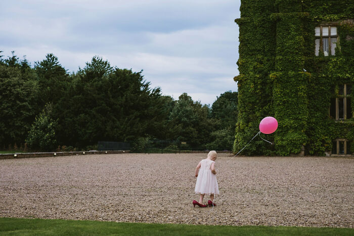 An image from the Street Photography Awards featuring a little girl in a white dress walking with a pink balloon.