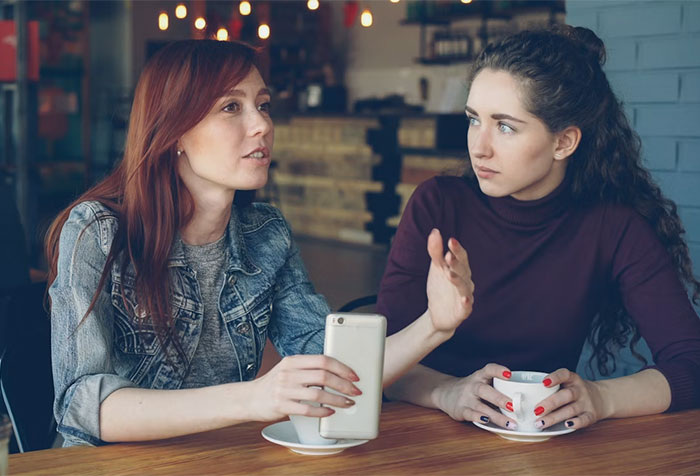Two women at a cafe discussing an entitled woman and a photographer's response.